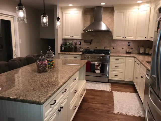 A kitchen with white cabinets and granite counter tops.